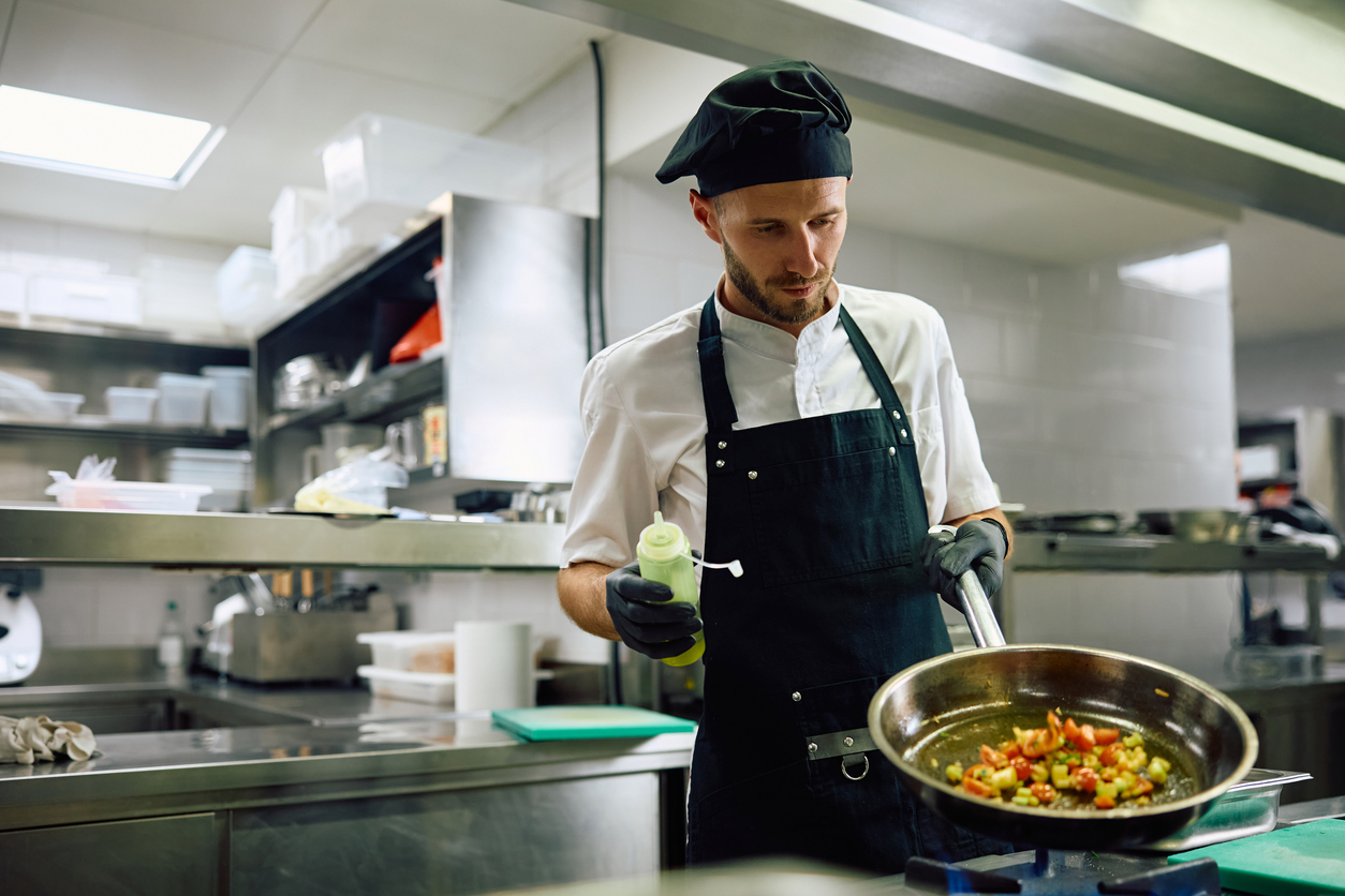 Male cook preparing food in restaurant kitchen.